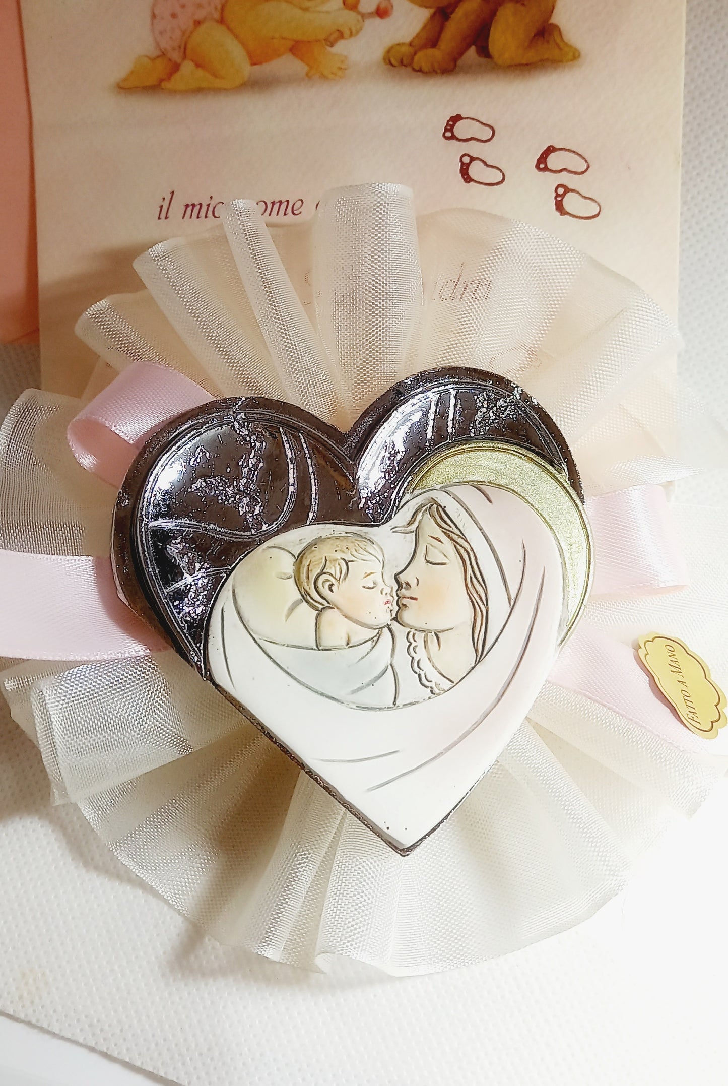 Bomboniera con icona artigianale della Madonna e Bambino, arricchita da dettagli dorati e una croce argentata brillante, applicata su una coccarda in tulle bianco con fiocco azzurro. Contiene 5 confetti e un bigliettino con nome e data.
Bomboniera con icona artigianale della Madonna e Bambino, arricchita da dettagli dorati e a forma di cuore argentata, applicata su una coccarda in tulle bianco con fiocco rosa. Contiene 5 confetti e un bigliettino con nome e data.