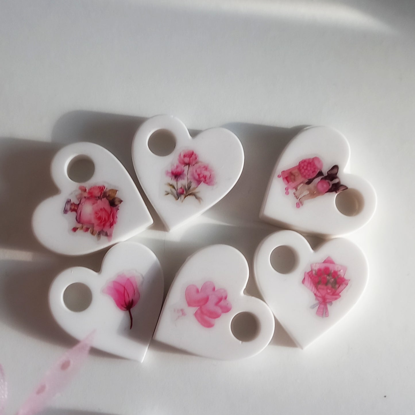 Cuoricini in gesso bianco con decorazioni floreali in rilievo, ideali per bomboniere.