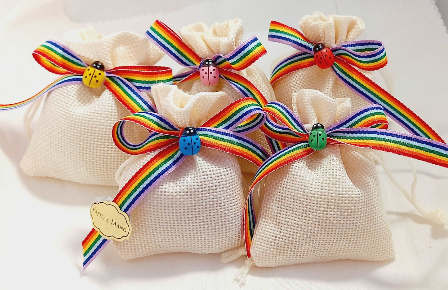 Bomboniere composte da sacchettino in tela di juta ecru con nastro multicolore che può essere sostituito con i colore che preferite. In abbinamento adorabili coccinelle in legno colorate, GIALLA ,AZZURRA,ARANCIONE,VERDE E ROSA