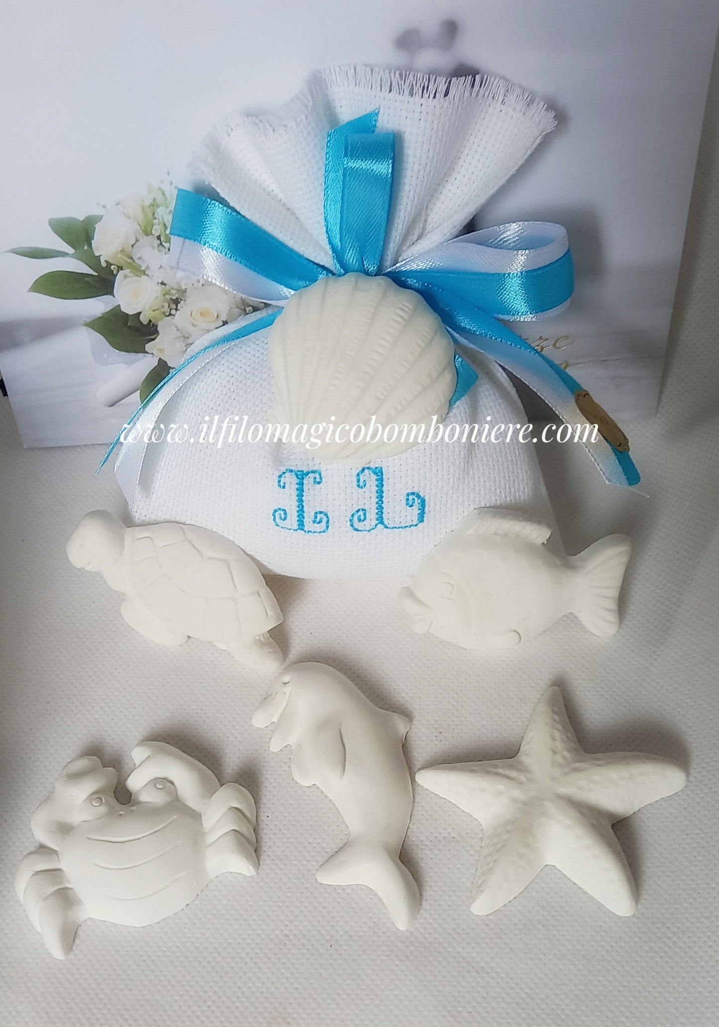 bomboniera matrimonio con sacchettino bianco con iniziali ricamate in color turchese e chiuso con nastri in tinta in abbinamento gessetti stile marino