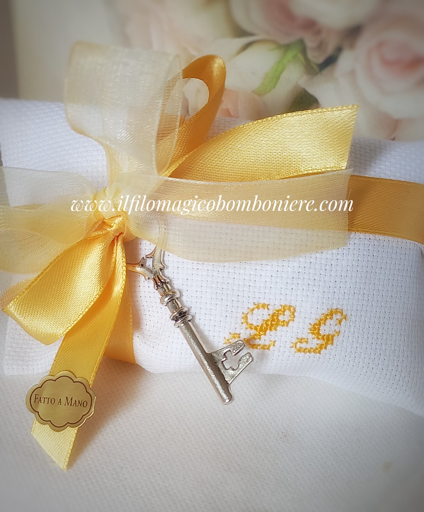 bomboniera matrimonio composte da busta bianca cin iniziali dei nomi degli sposi ricamate in giallo chiusa con nastri organza e raso giallo e ciondolo chiave