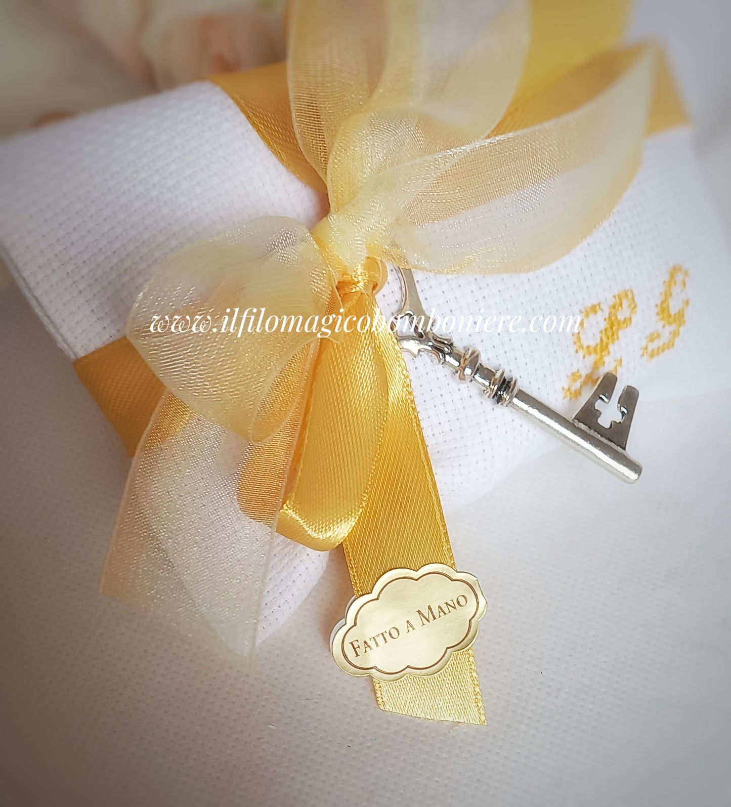 bomboniera matrimonio busta bianca con iniziali dei nomi ricamate a mano in color giallo oro nastri organza e raso in tinta con il ricamo ciondolo chiave e etichetta con scritta Fatto a Mano