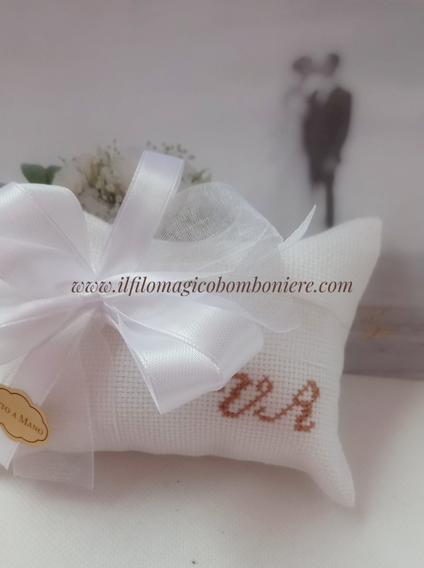 bomboniere nozze busta bianca con iniziali dei nomi ricamate in marrone chiusa con fiocchi raso e organza bianchi