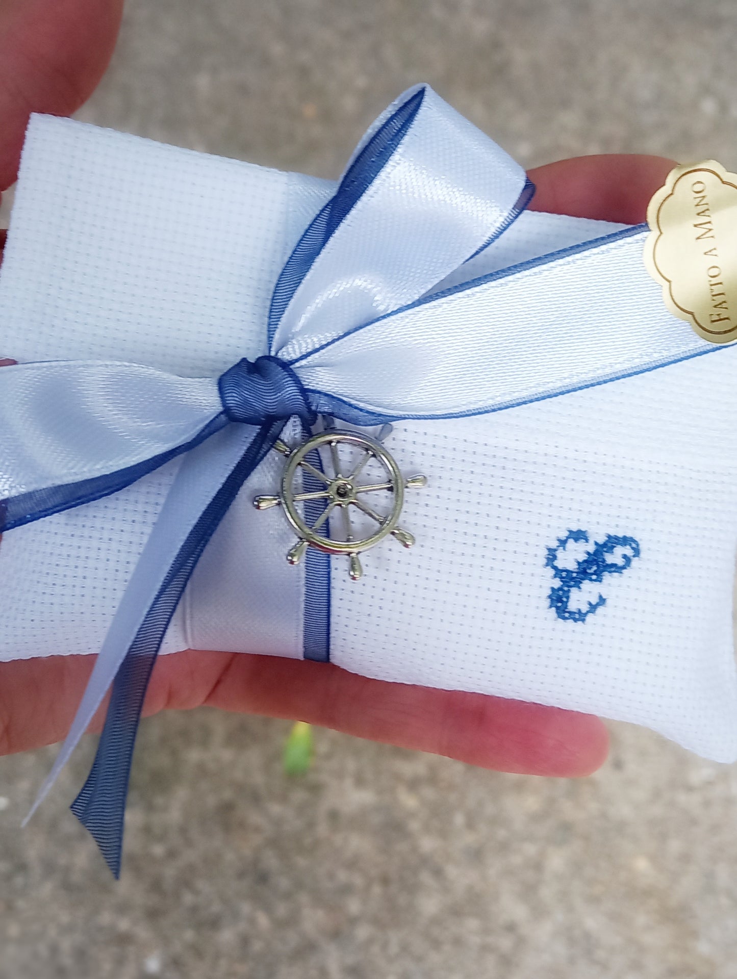 bomboniera comunione o cresima composta da busta con iniziale ricamata in blu e fiocchi raso bianco e organza blu con ciondolo timone.