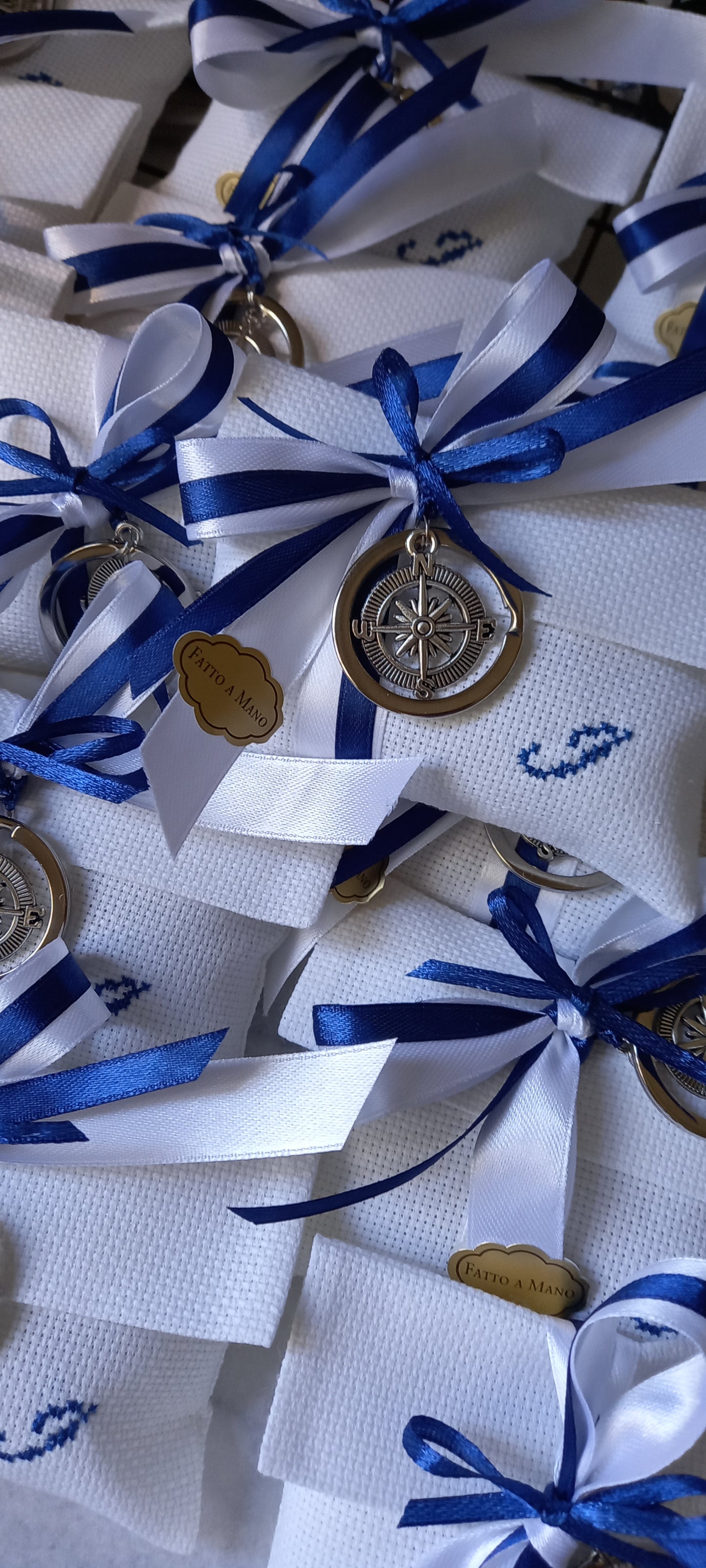 Fiocchi in raso blu e bianco con ricamo personalizzato e charm bussola su tessuto bianco pregiato