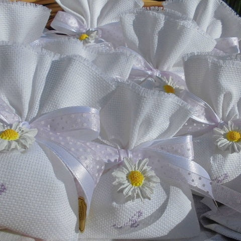 bomboniere comunione o cresima bimba composta da sacchettino bianco con iniziale del nome ricamata a mano e in abbinamento margherita realizzata a mano in polvere ceramica