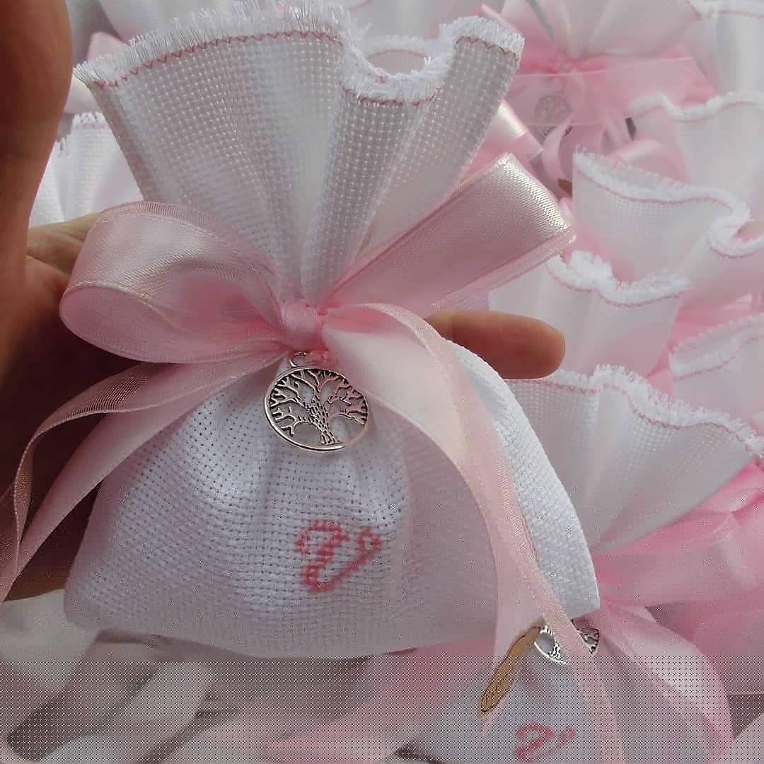 bomboniere battesimo comunione o cresima composte da sacchettino bianco con iniziale del nome ricamata a mano in rosa e in abbinamento ciondolo albero della vita tondo in silver-plated