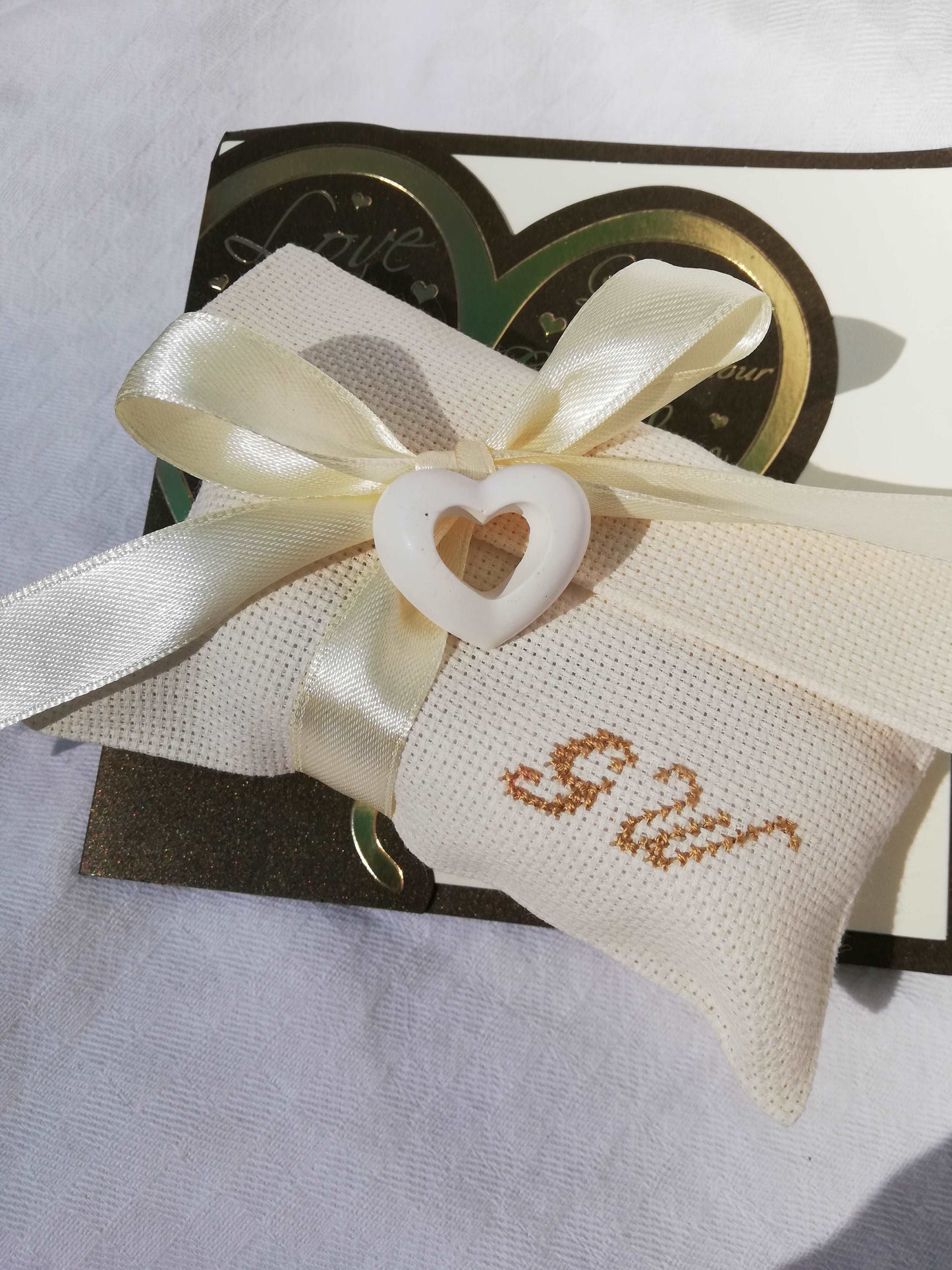 bomboniere matrimonio composte da busta ecru con iniziali dei nomi degli sposi ricamate a mano e in abbinamento cuore forato profuma biancheria realizzato a mano