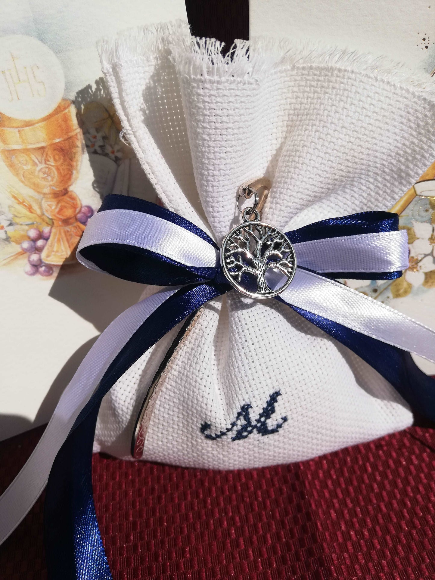 bomboniere prima comunione o cresima bimbo composta da sacchettino bianco con iniziale del nome ricamata a mano in blu e in abbinamento segnalibro albero della vita argentato