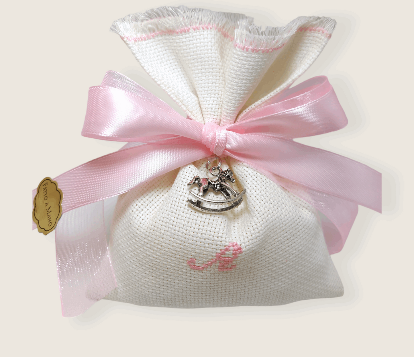 bomboniera battesimo sacchettino bianco con iniziale del nome ricamata in rosa nastri raso rosa e bianco e ciondolo cavallo a dondolo