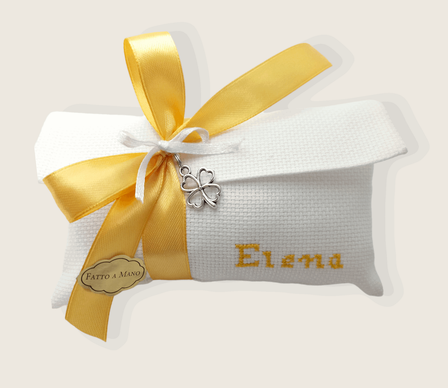 bomboniera composta da busta bianca con nome ricamato in giallo e nastro raso giallo e ciondolo quadrifoglio