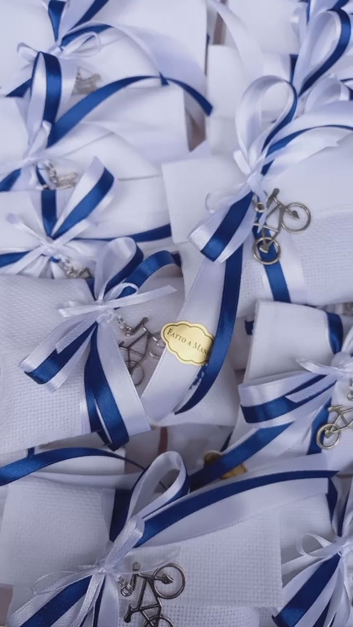 bomboniere prima comunione o cresima bimbo busta bianca con iniziale del nome ricamata in blu nastri raso bianco e blu e ciondolo bicicletta