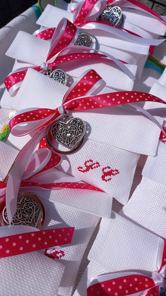 Celebra la Prima Comunione o la Cresima della tua bambina con stile. Buste bianche con iniziali fuxia, legate con nastri di raso bianco e fuxia a pois, abbinate a portachiavi cuore in silver-plated. Un ricordo speciale per un giorno sacro.