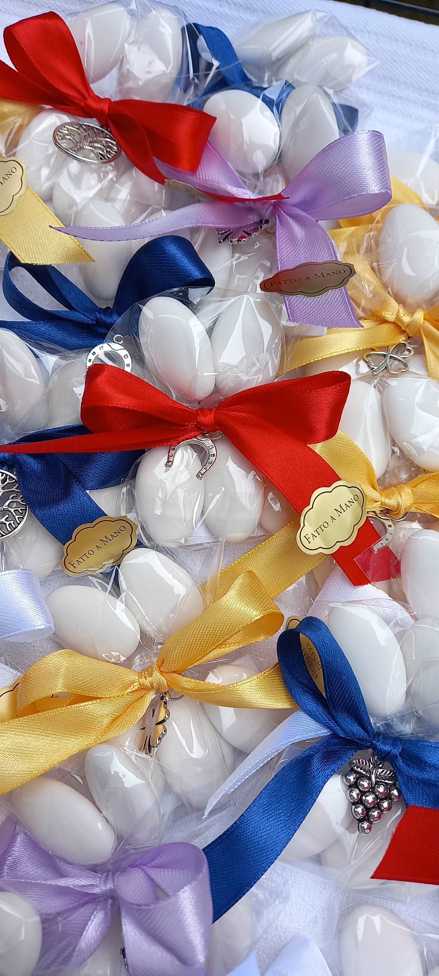 bomboniere per qualsiasi ricorrenza composte da 5 confetti avvolti in carta alimentare legati con nastri giallo, lilla, blu, rosso e bianco e ciondoli ferro di cavallo quadrifoglio, grappolo uva e albero della vita