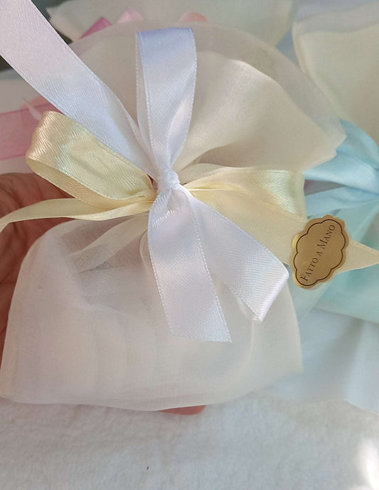 Sacchettino porta confetti in organza avorio chiuso con fiocco bianco ed ecru, etichetta "Fatto a mano " visibile sul lato.