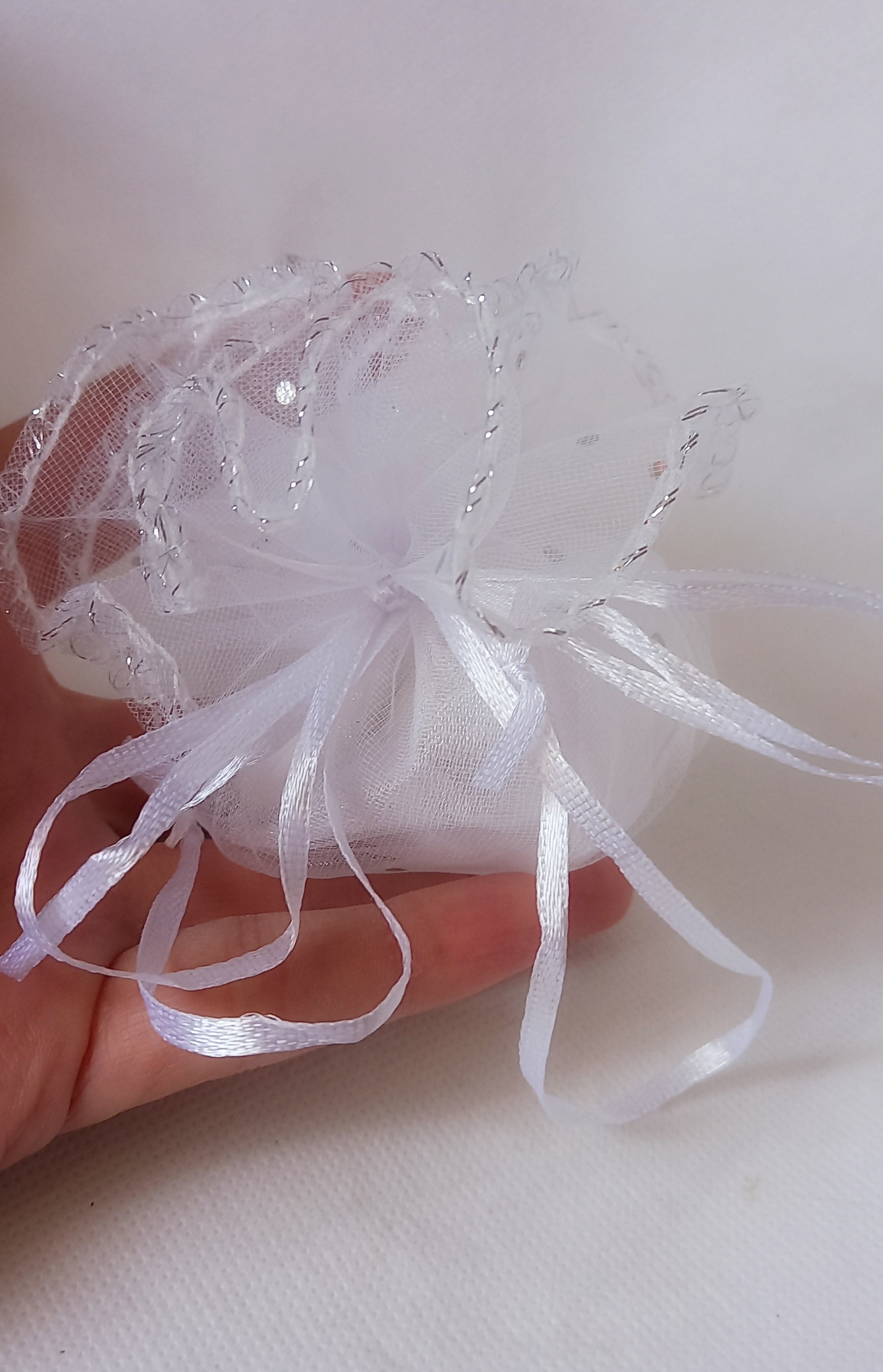 Sacchettino in tulle bianco con dettagli argentati, perfetto per contenere confetti in occasione di comunione, matrimonio o anniversari d'argento.