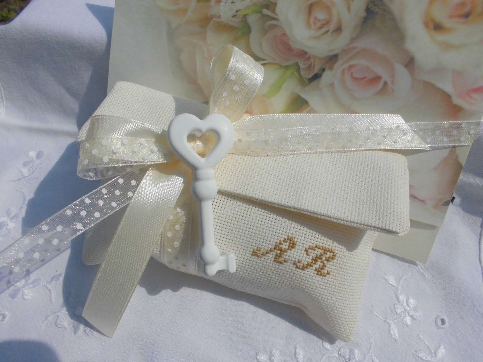 bomboniera matrimonio composta da busta ecru porta confetti 12 cm x 15 cm con iniziali dei nomi degli sposi ricamate a mano e in abbinamento chiave profuma bianche