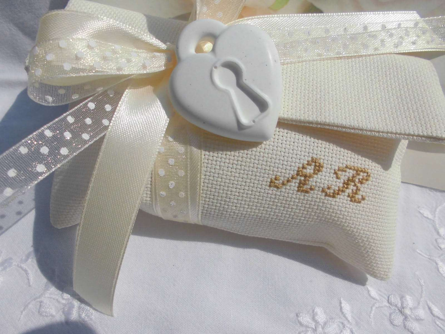 bomboniera matrimonio composta da busta ecru porta confetti 12 cm x 15 cm con iniziali dei nomi degli sposi ricamate a mano e in abbinamento cuore lucchetto profuma bianche