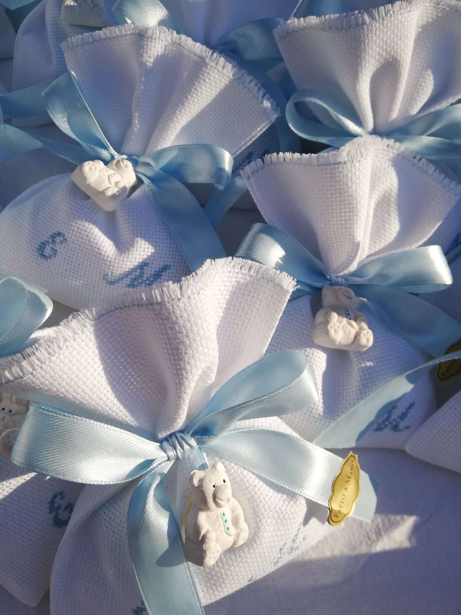 bomboniere per gemmeli composte da sacchettino bianco porta confetti con iniziali dei nomi dei bambini ricamate a mano in azzurro e in abbinamento orsetto profuma biancheria