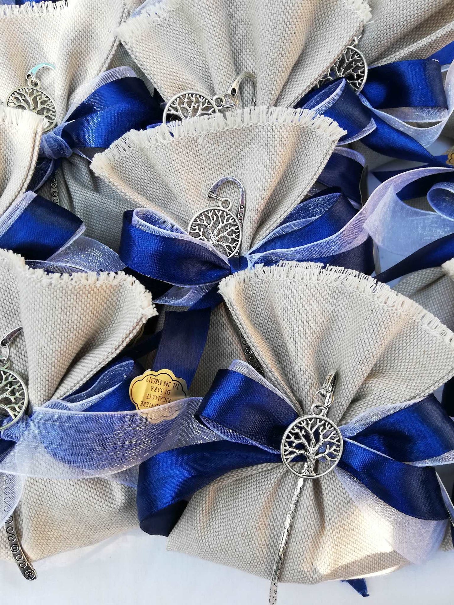 bomboniere comunione o cresima bimbo composte da sacchettino in lino grezzo nastri raso blu e organza bianco e segnalibro albero della vita argentato