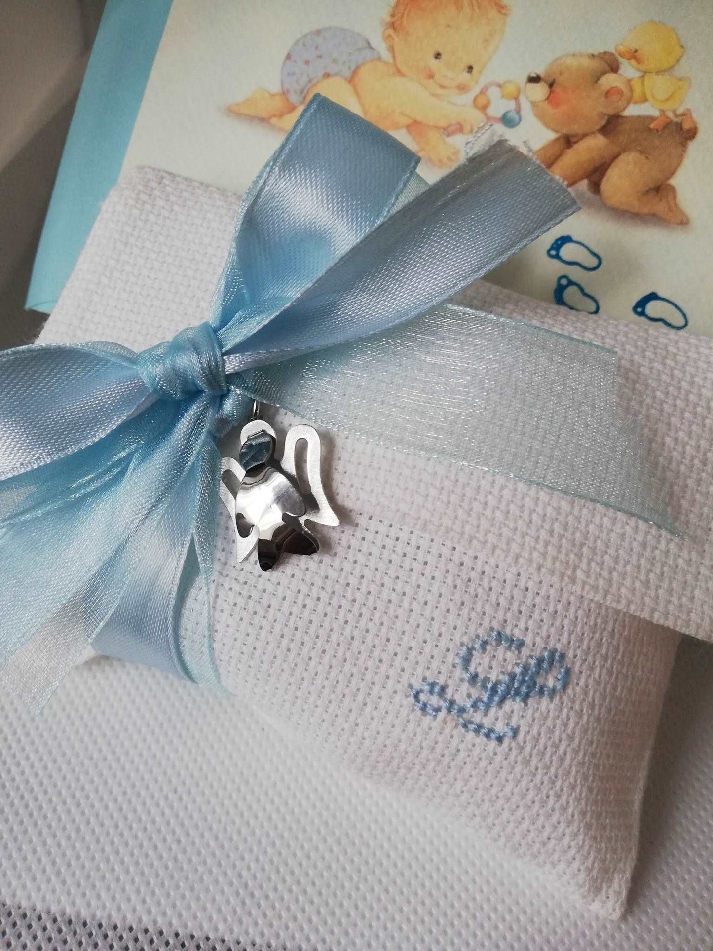 bomboniere battesimo bimbo composte da busta bianca con iniziale del nome ricamata a mano in azzurro e ciondolo angelo in argento 925